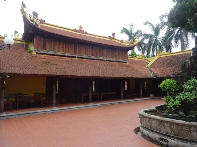 A temple complex with red tiled roofs and palm trees in the courtyard