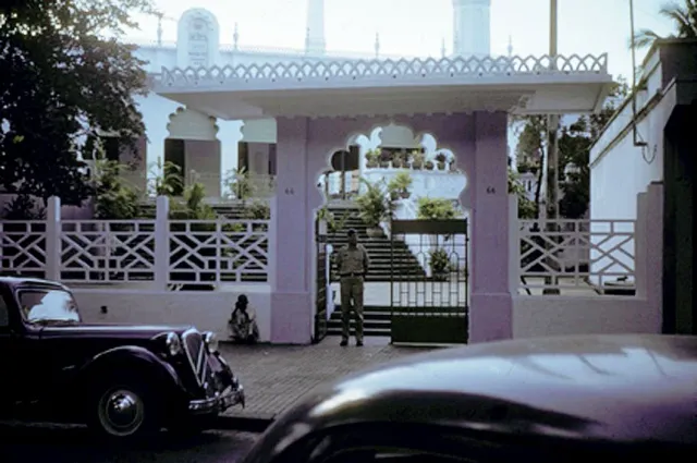 A white mosque gate with a dome and a vintage car parked in front