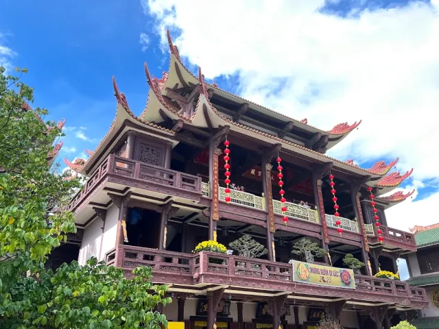A two story wooden building with upswept roofs and long strings of red lanterns