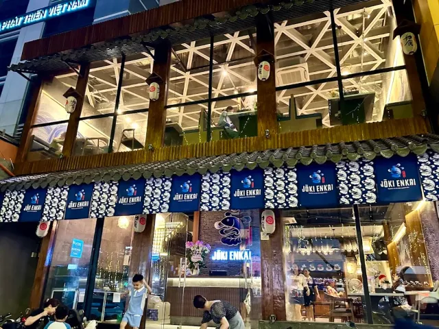 A two story front in the evening with blue fabric curtains, paper lanterns and a tiled roof