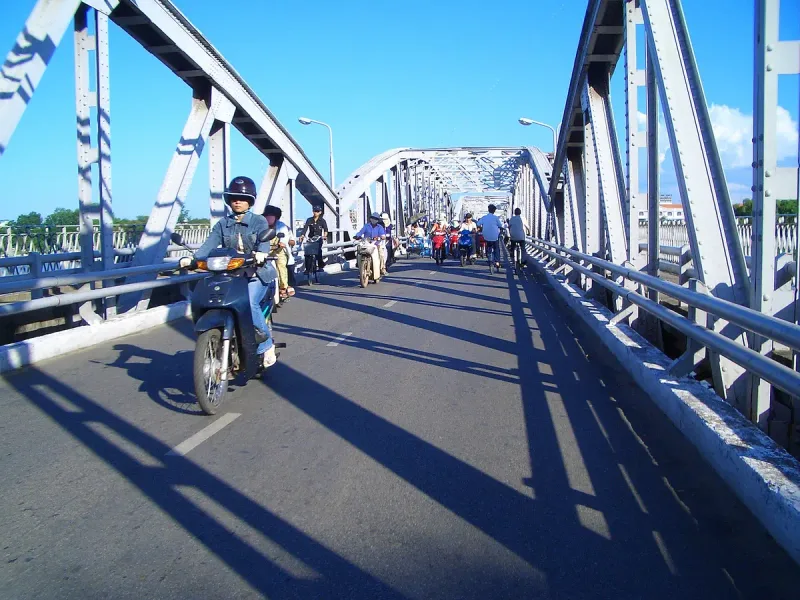Inside the Truong Tien bridge in Hue, blue steel arches with a motorcyclist crossing