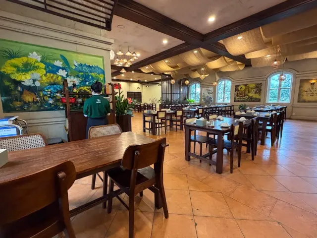 A wide dining hall with wooden tables, a beamed ceiling and a large lily mural