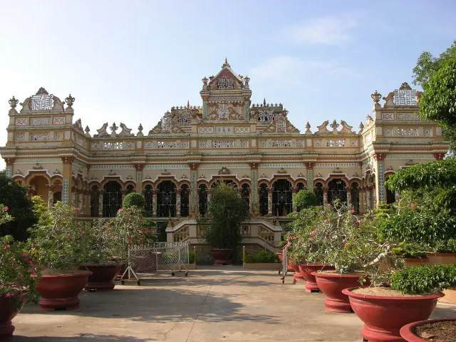 An ornate white temple facade with potted plants along the steps