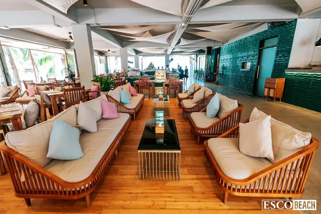 Wooden sofas with pastel cushions in a covered hall open to palm trees