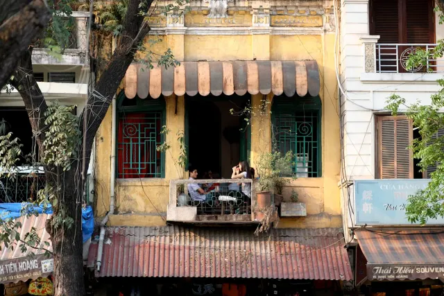 The yellow front of a cafe in an old building with a striped awning