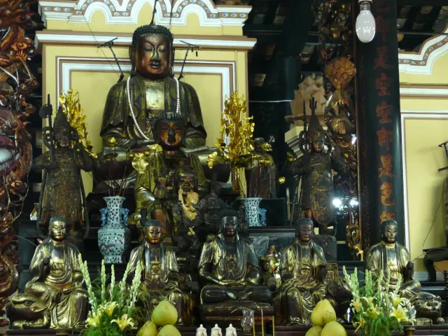 A main altar crowded with gilded Buddha figures in dim temple light