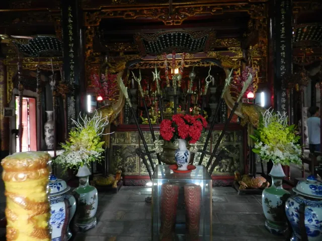 A temple interior with large urns, red flowers and warm lighting