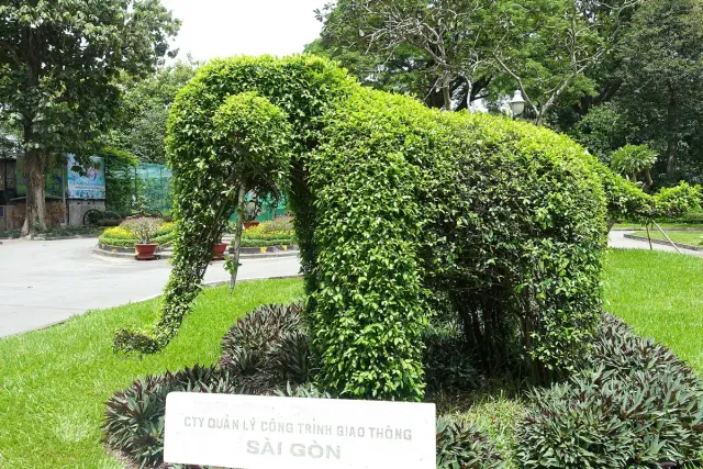 An elephant topiary in a manicured public garden with lawn and flower beds